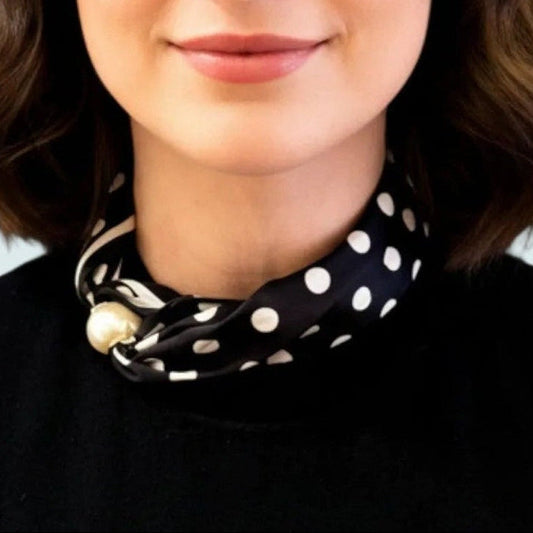 Kendall wearing a black sleeveless top with a polka dot scarf against a light blue background